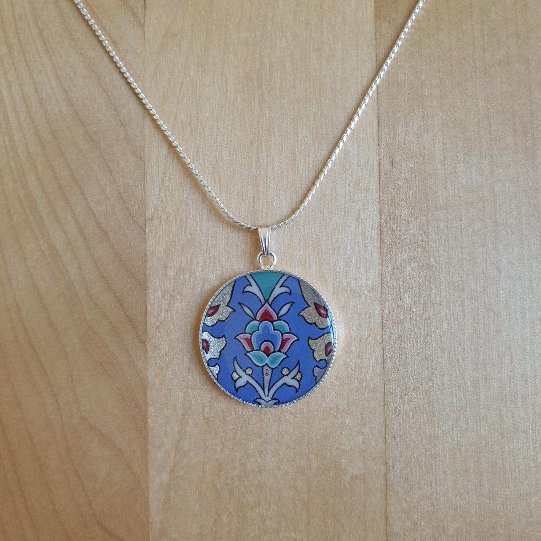 Collier pendentif fleur et arabesques sur fond bleu